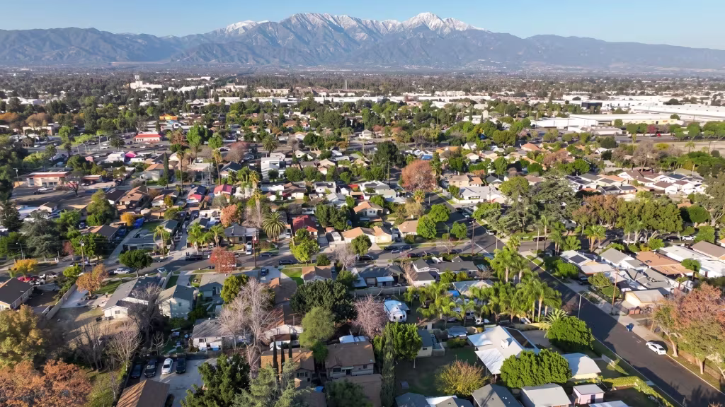 Aerial panorama over Ontario, a broad residential cityscape beneath snow-capped mountains