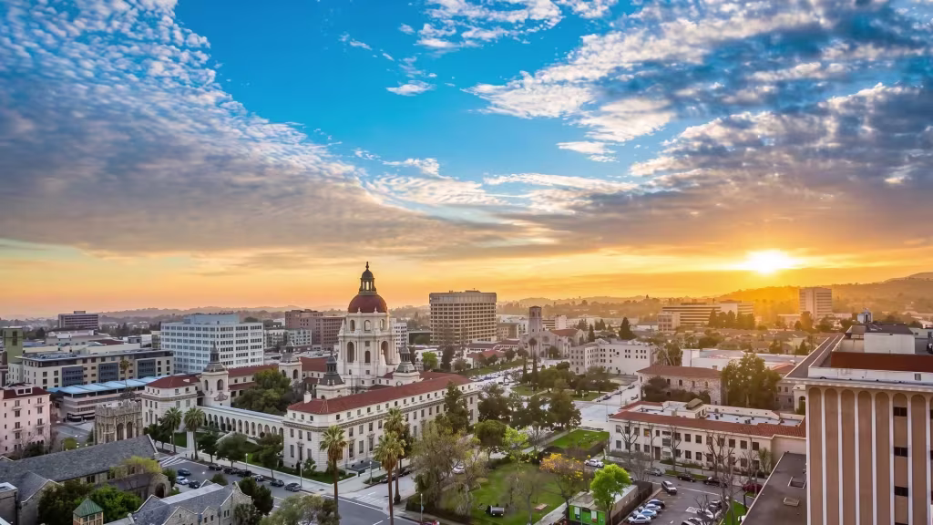 Elevated view over Pasadena's civic skyline at sunset, with mountains rising behind the city