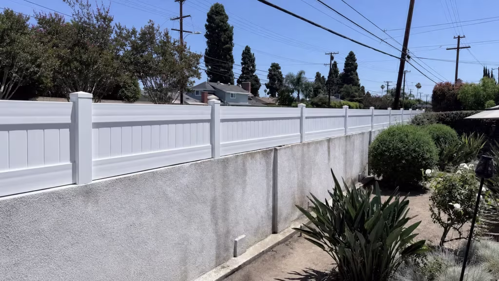 Bird-of-paradise clumps and roses crowd the base of this Garden Grove yard's White vinyl wall topper, added for privacy