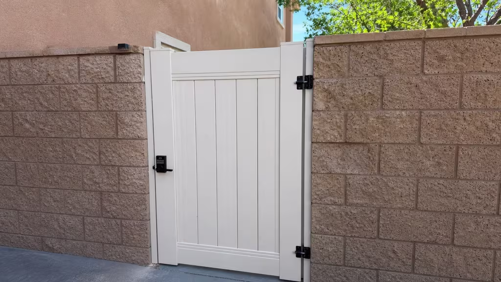A white-trimmed window looks over the stucco wall behind this Tan vinyl privacy gate in a Los Angeles side passage