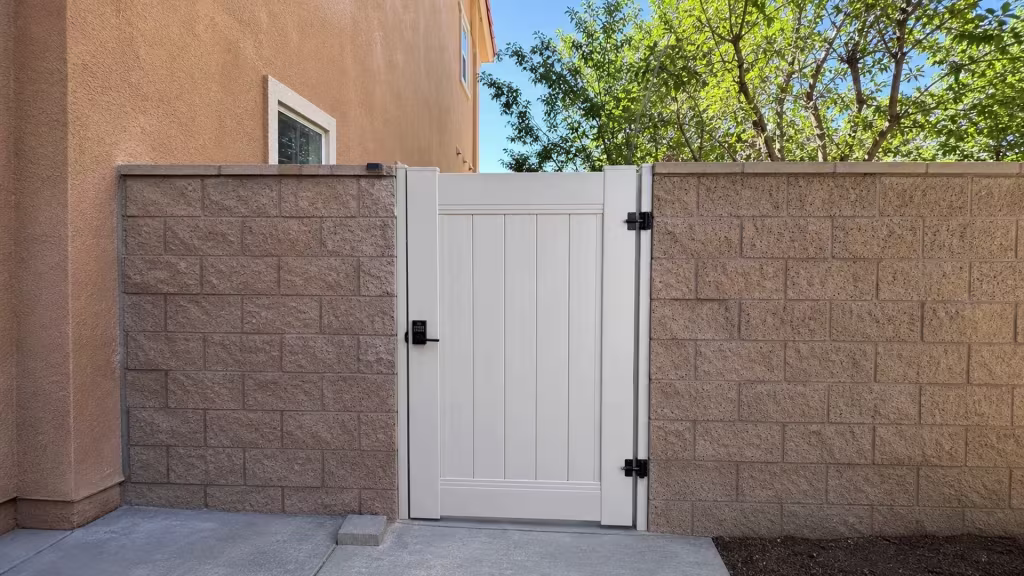 In Los Angeles, a small concrete step sits at the foot of this Tan vinyl gate set between concrete block walls