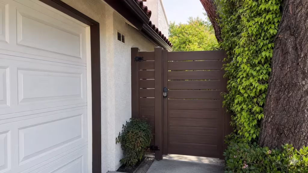 Denser lower boards and a narrow reveal spacing mark this Dark Walnut vinyl gate beside its fixed panel