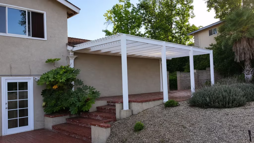 White vinyl lattice patio cover built lean-to style against the house, its beams resting on a terrace