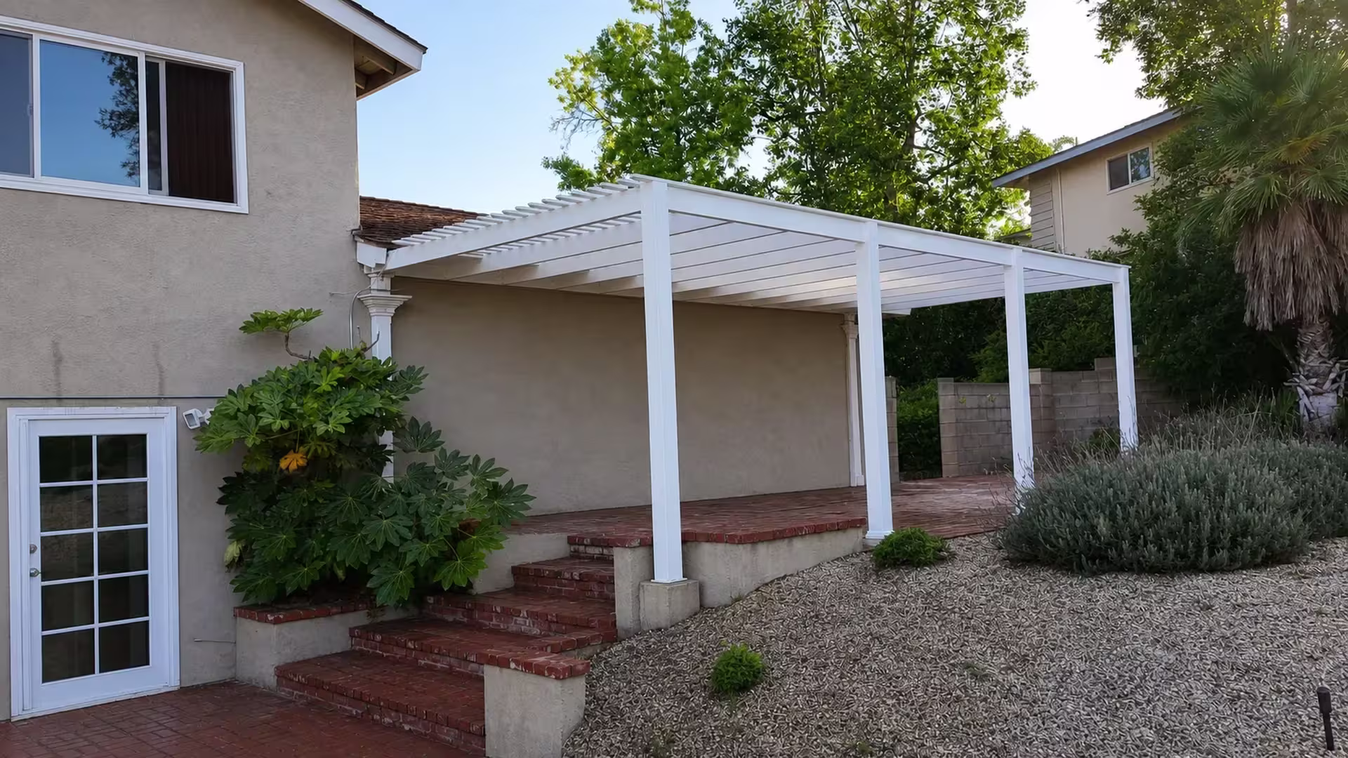 White vinyl lattice patio cover built lean-to style against the house, its beams resting on a terrace