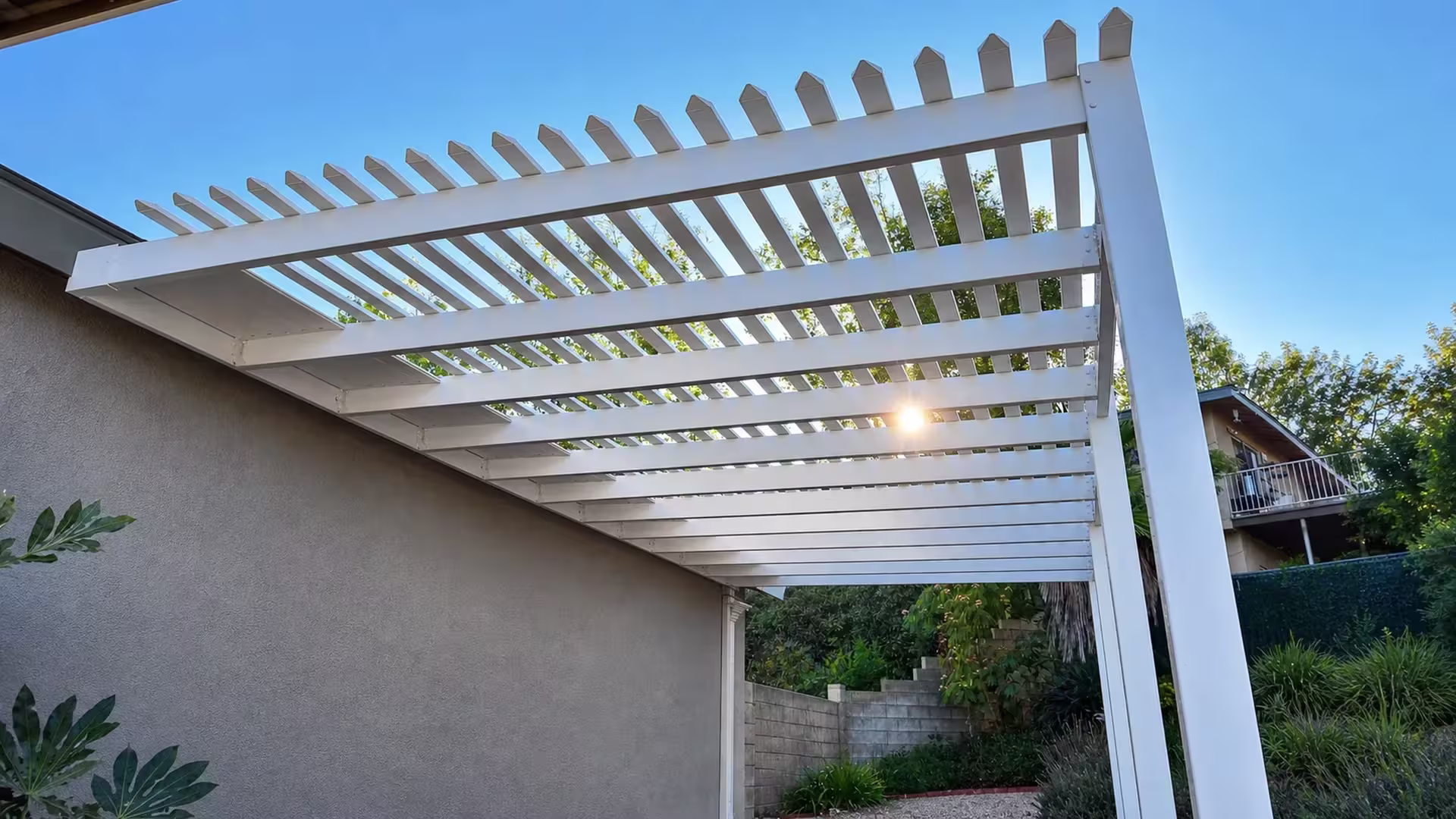 White vinyl pergola cover viewed from below, its square front post topped with a pointed pyramid cap