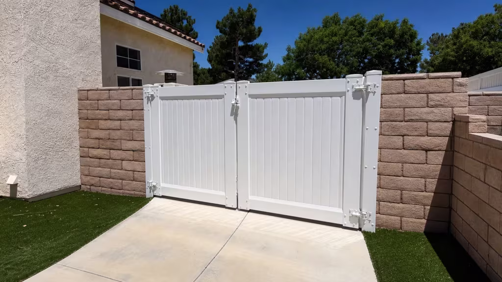 White vinyl double privacy gate spanning a driveway opening between two block walls in Palmdale