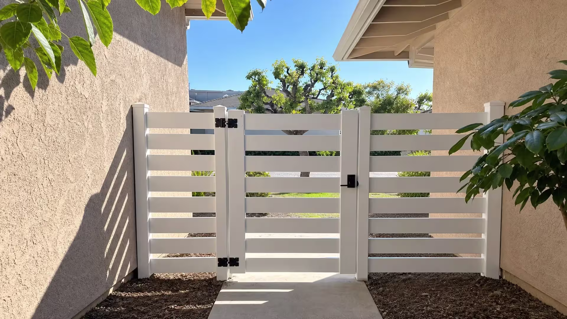 A White vinyl horizontal picket gate sits centered between square posts, with matching fence panels on both sides