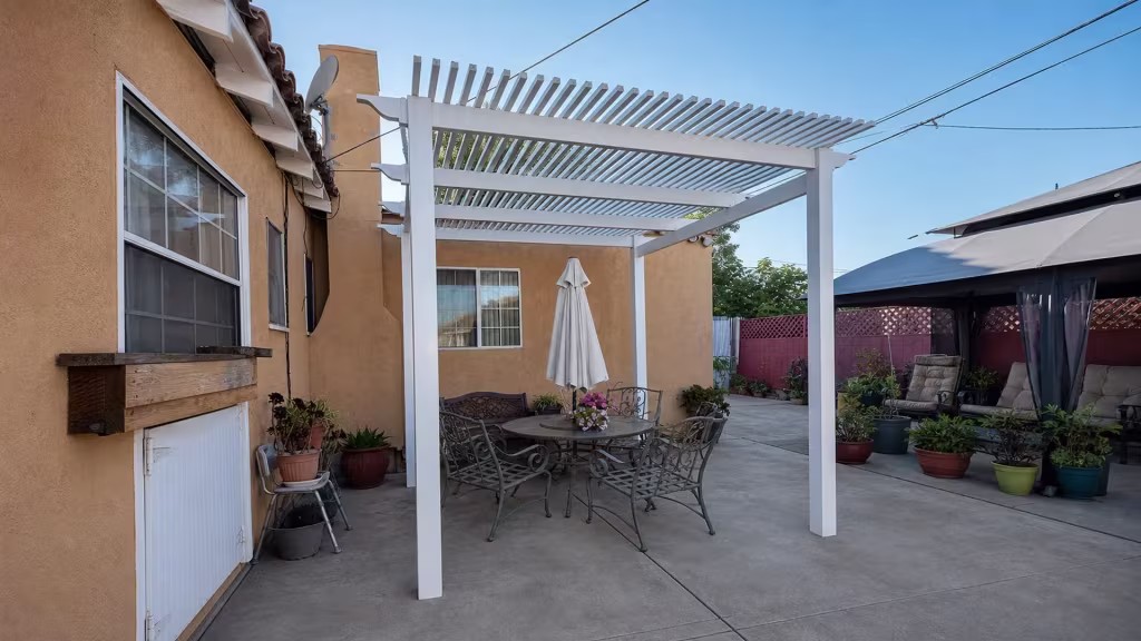 Patio furniture and a closed umbrella furnish this Long Beach courtyard under a White vinyl lattice patio roof cover