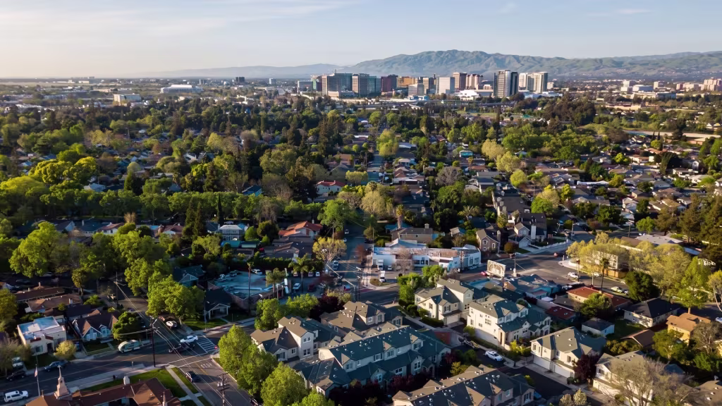Tree-rich neighborhoods sit beneath an urban skyline and distant mountains in this panorama of Santa Clara