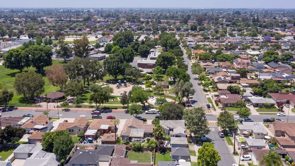 A residential grid and open green civic space spread across this aerial panorama over Santa Fe Springs