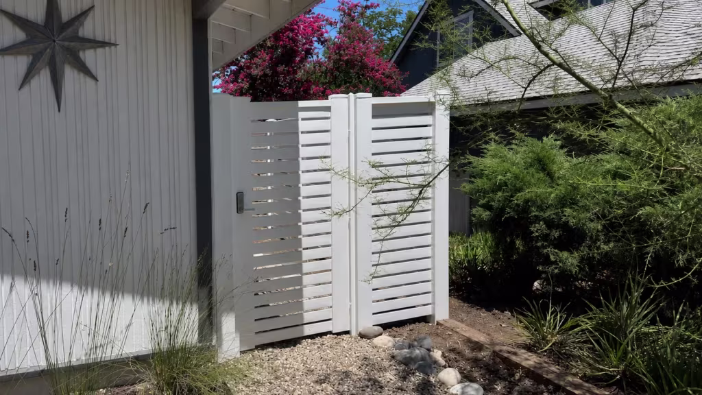 A steep gray roof and dark gable rise above this White manufactured-vinyl horizontal picket fence and gate in Granada Hills