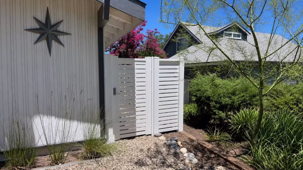 A gravel yard closes with this White vinyl horizontal picket fence, finished with dark latch hardware