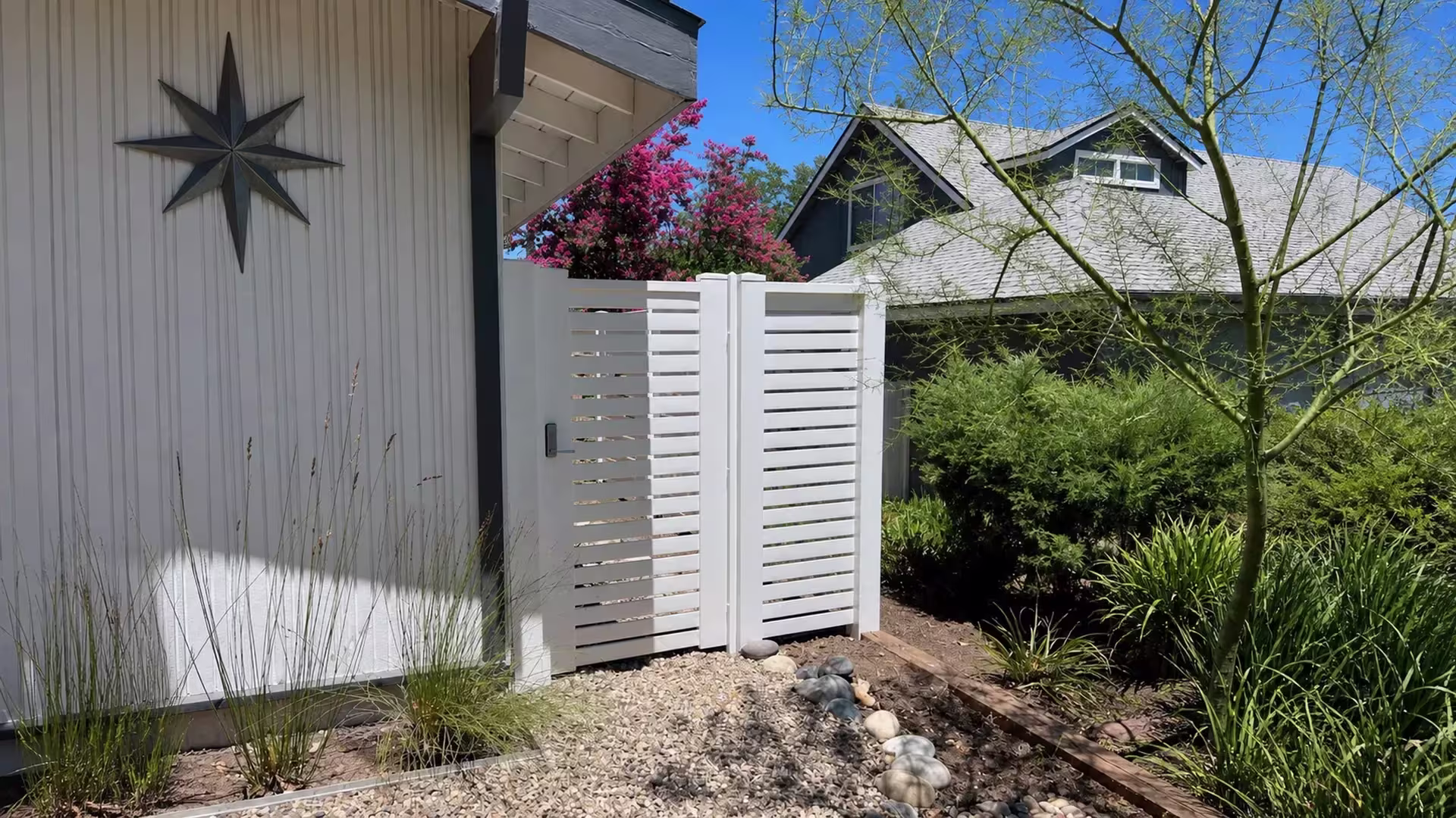 A gravel yard closes with this White vinyl horizontal picket fence, finished with dark latch hardware