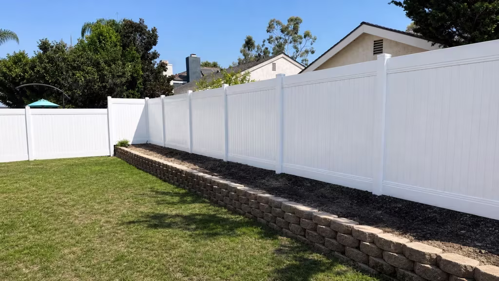 This Laguna Hills yard has neighboring stucco rooflines and roof vents rising behind its White vinyl privacy fence