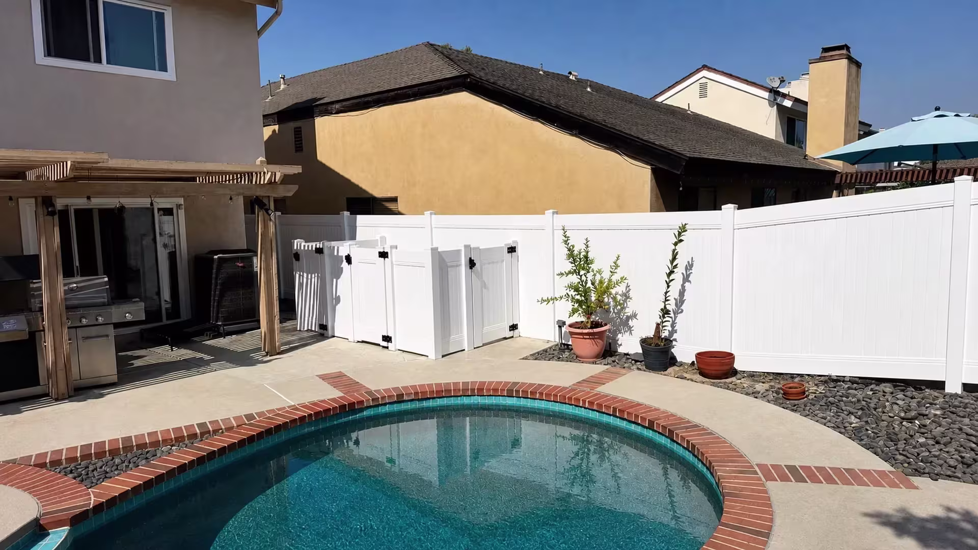 In this Laguna Hills yard, a wooden patio pergola and potted plants sit beside the White vinyl privacy fence