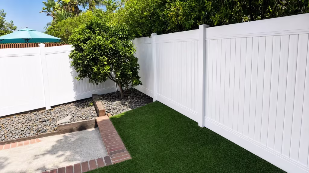 A stone-filled planting bed borders this White vinyl privacy fence wrapping around the corner in Laguna Hills
