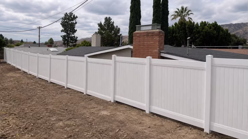 A gentle grade change carries this White vinyl fence across evenly spaced shared posts in Sunland