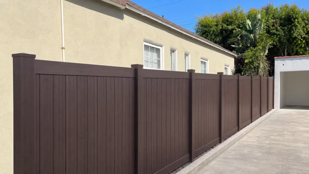 Bird of paradise planting lines this Dark Sequoia vinyl fence along a narrow Los Angeles side yard