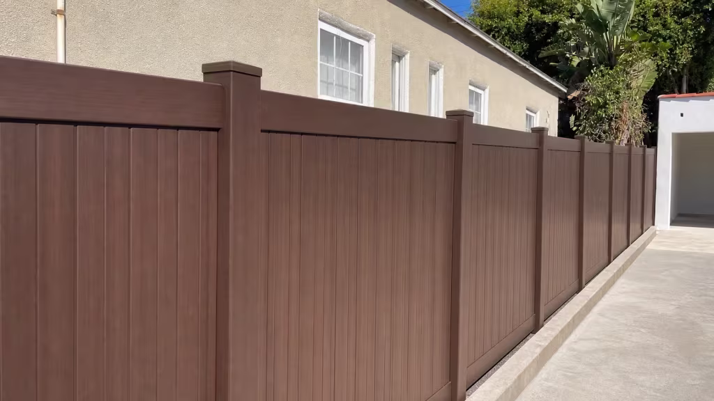 Dark Sequoia vinyl privacy fence boards fit tightly against square posts beside a cream stucco wall in Los Angeles