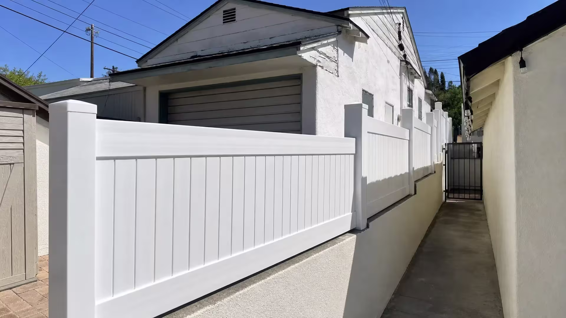 A gray garage door and gabled roofline overlook this Glendale driveway's White vinyl topper, added there for privacy