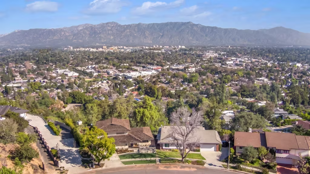 Elevated panorama over South Pasadena, leafy hillside neighborhoods set against mountains behind them