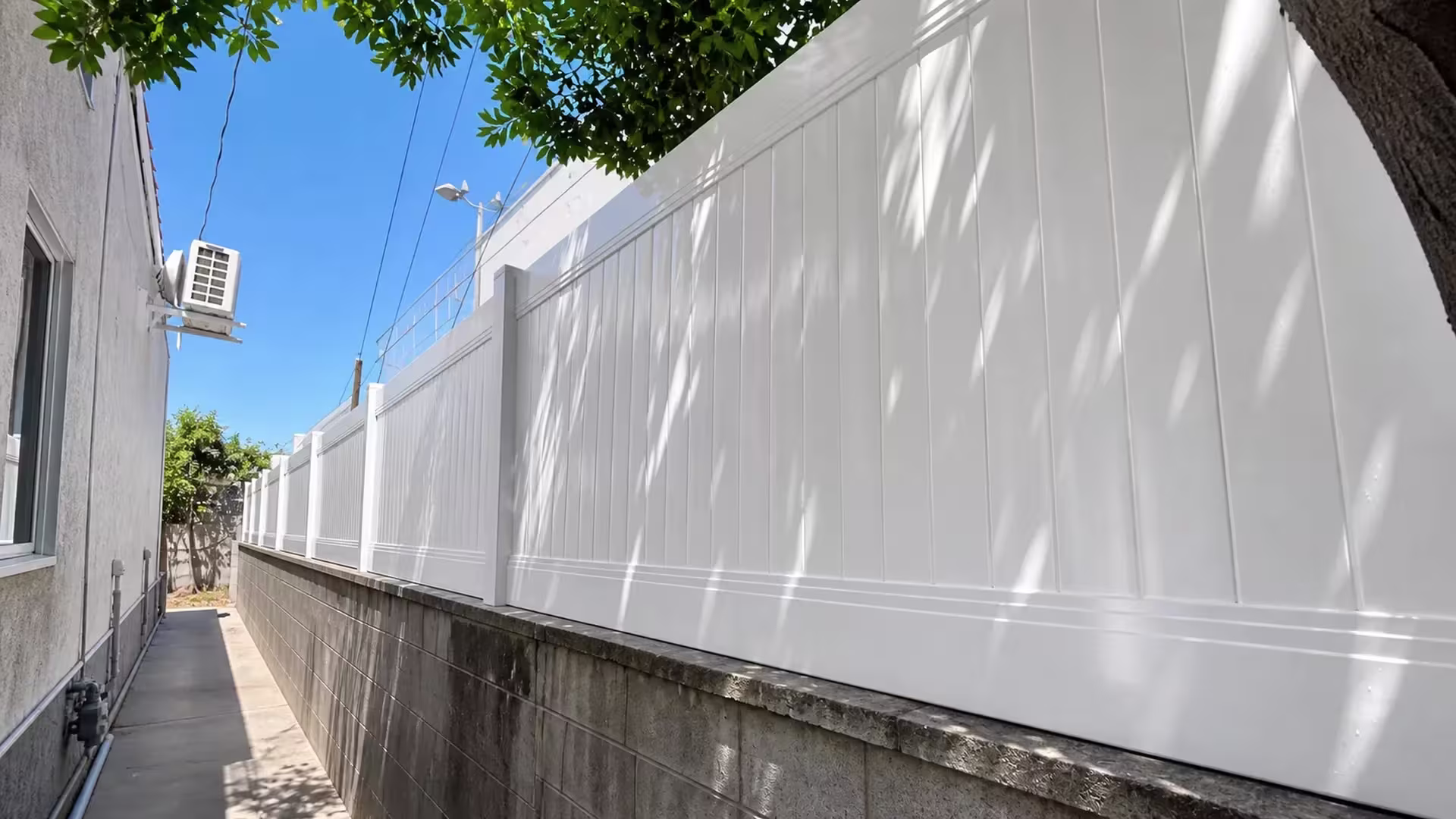 A gray block wall in West Hollywood carries this White vinyl privacy-and-acrylic fence along its capped top