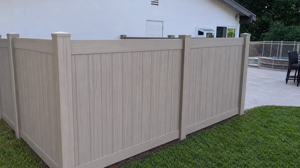 A white door and windows mark the stucco house wall beside this Coastal Cedar vinyl privacy fence in Encino