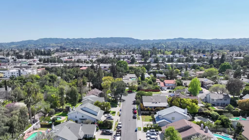 Elevated view over Tarzana, a leafy residential cityscape reaching toward distant hills