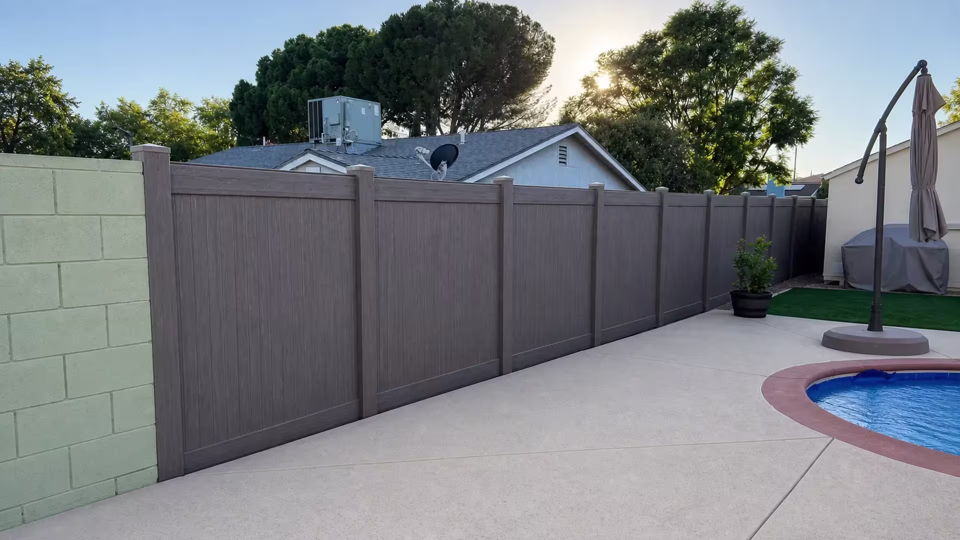 An HVAC unit and satellite dish top the neighboring roof above this Dark Walnut vinyl privacy fence line in Granada Hills