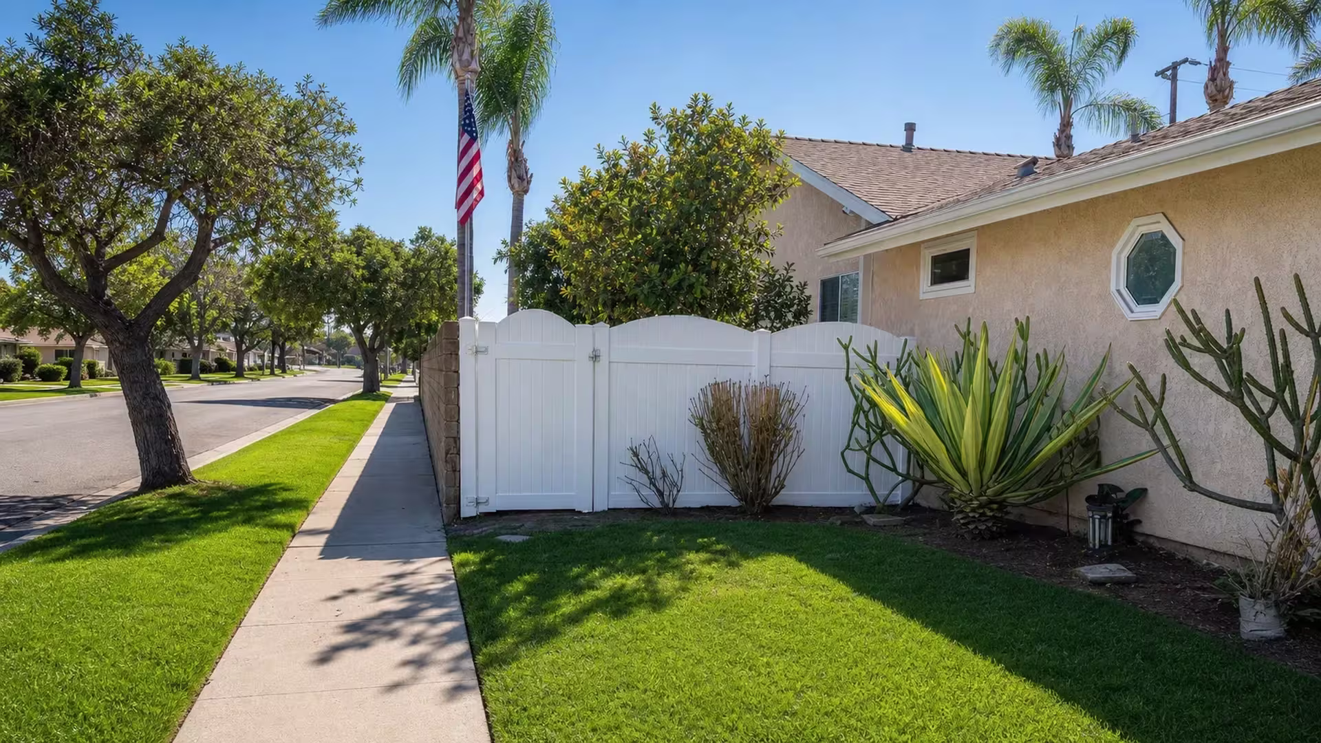 An American flag flies near this White vinyl privacy fence and gate in Huntington Beach