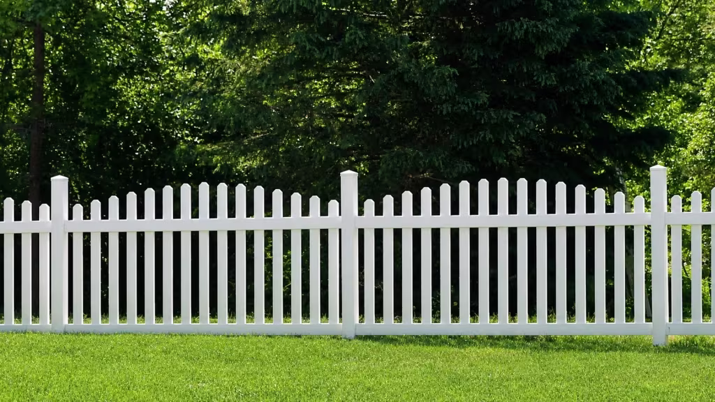 A straight run of White vinyl arched picket fence spans an open green lawn between two posts