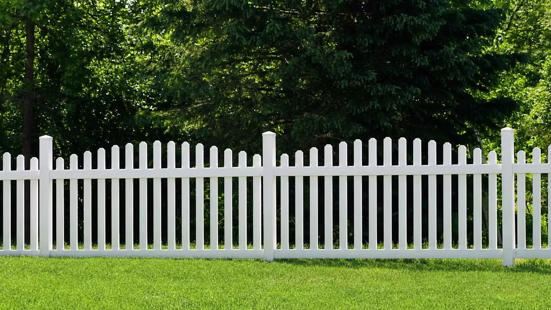 A straight run of White vinyl arched picket fence spans an open green lawn between two posts