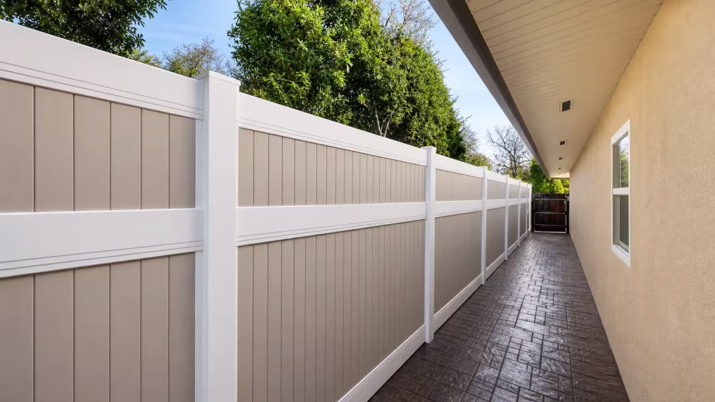 Vertical taupe infill boards inside white framing recede along a Beige vinyl fence toward the rear yard