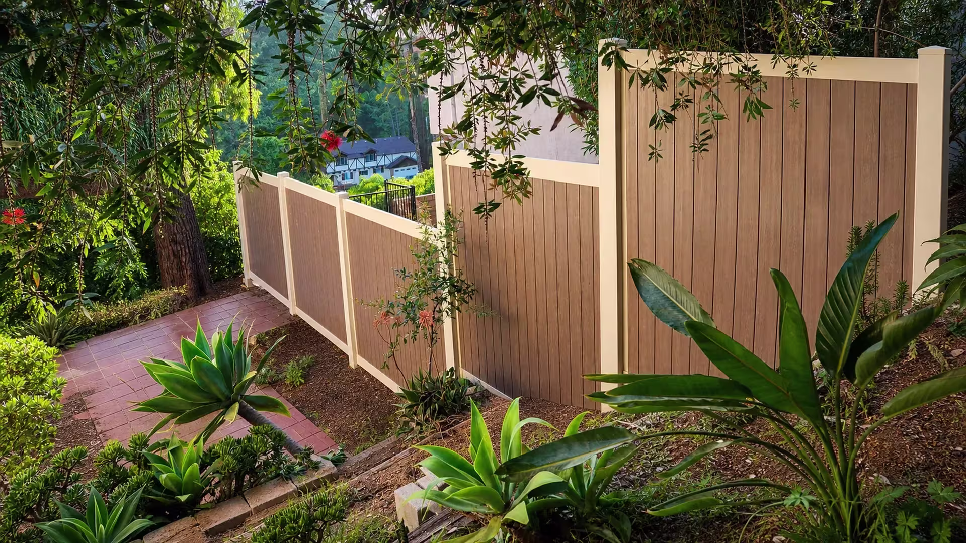 A stepped privacy line of Cream vinyl fence descends a steep planted garden slope in four sections