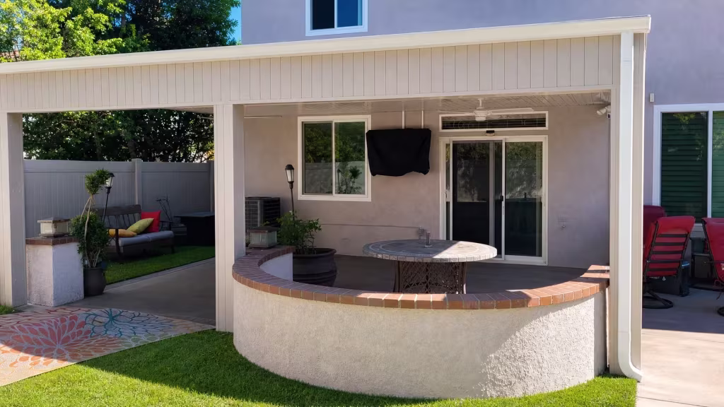 Tan vinyl custom patio cover set on three support posts beside a curved masonry counter and sliding door