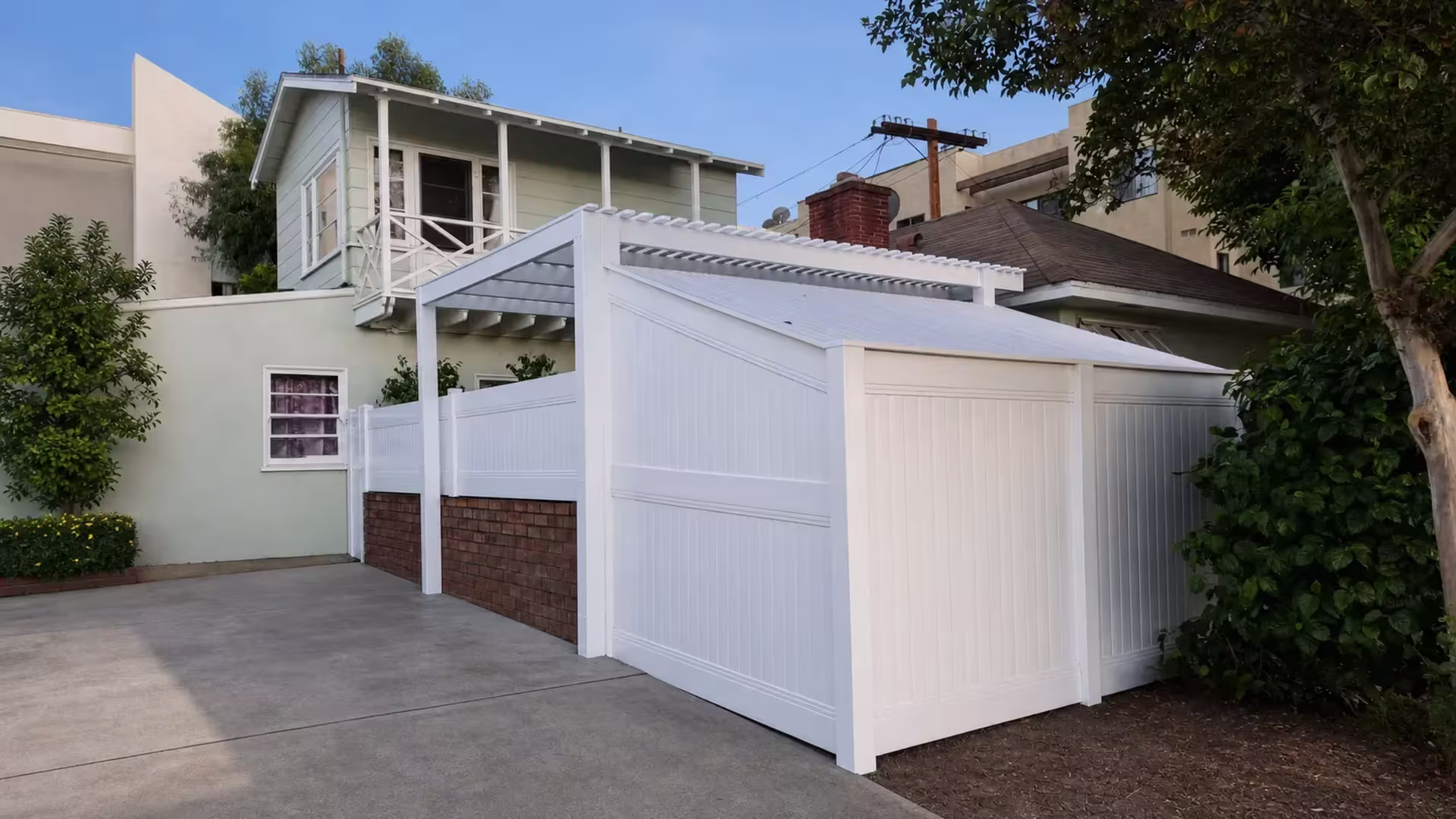 Tongue-and-groove privacy slats close one side of this custom-made White vinyl patio cover beside a concrete driveway