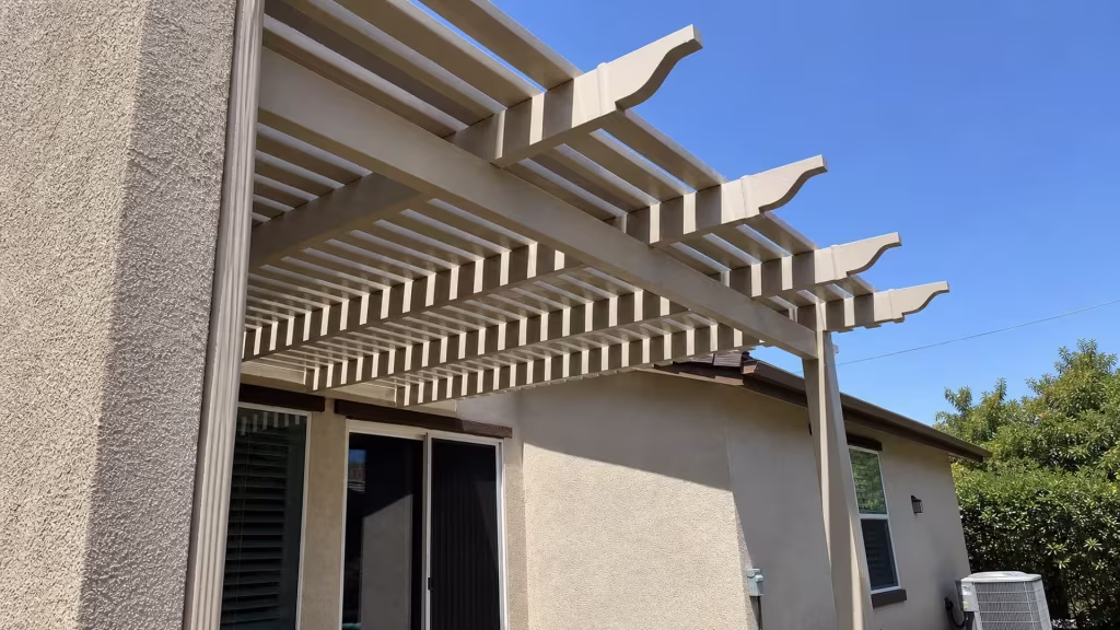 Attached alongside a textured stucco wall, this custom open-lattice patio cover of White vinyl passes an outdoor HVAC unit
