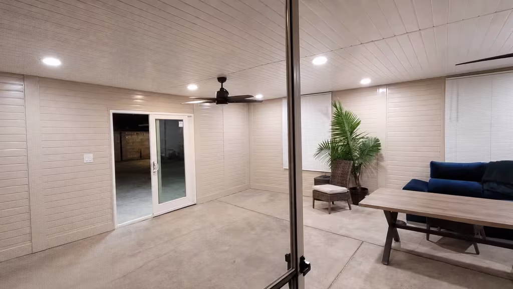 A tongue-and-groove ceiling caps this custom patio cover, formed in White vinyl, inside an enclosed patio room