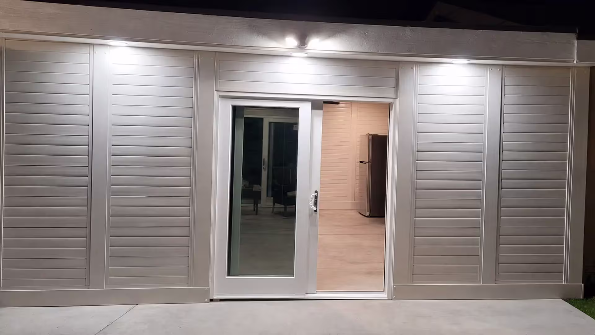 A central doorway and divider posts frame this custom patio cover's enclosed walls in White vinyl over a concrete slab