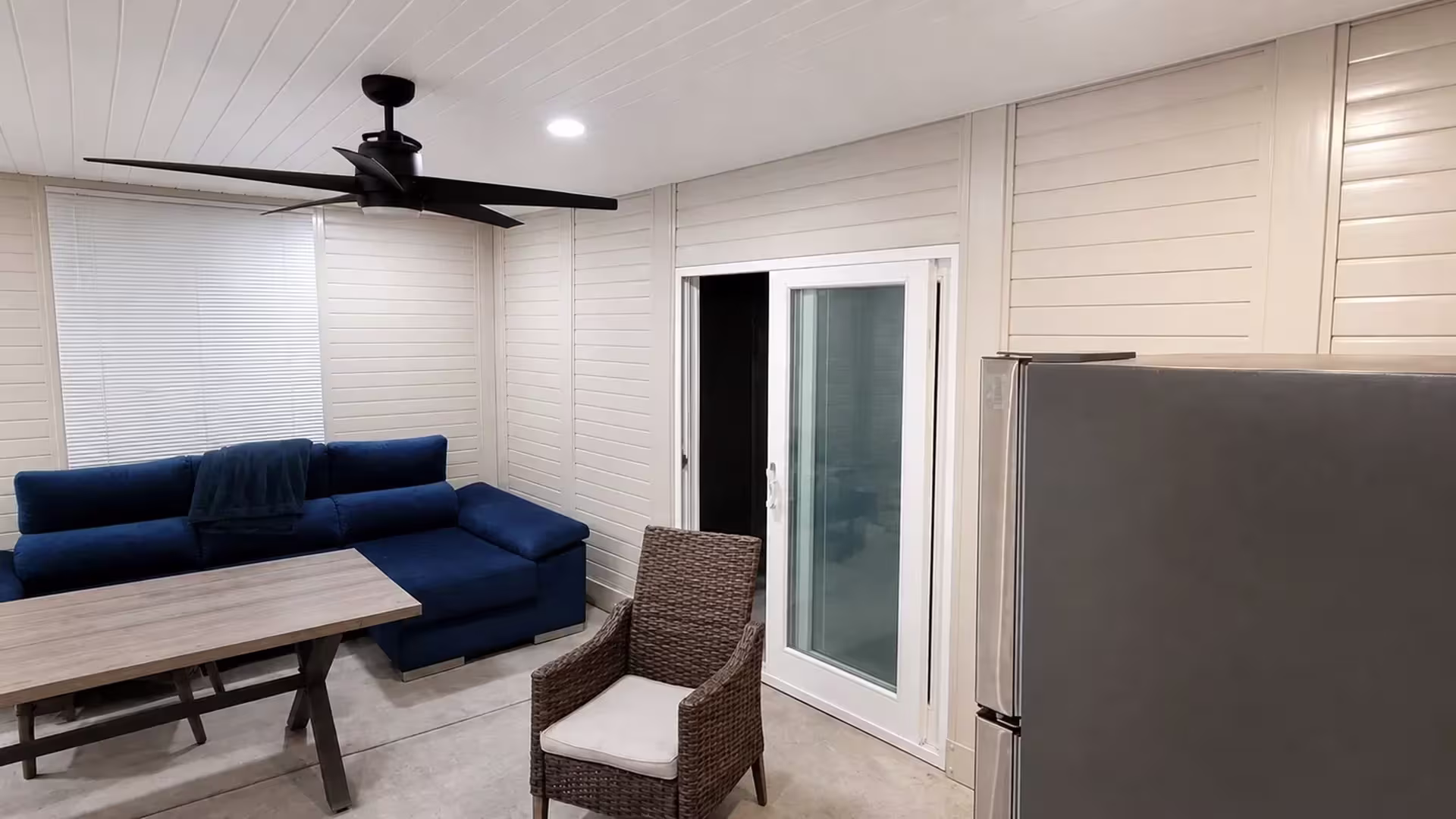 A five-blade ceiling fan and recessed lighting sit inside this enclosed custom patio cover made of White vinyl