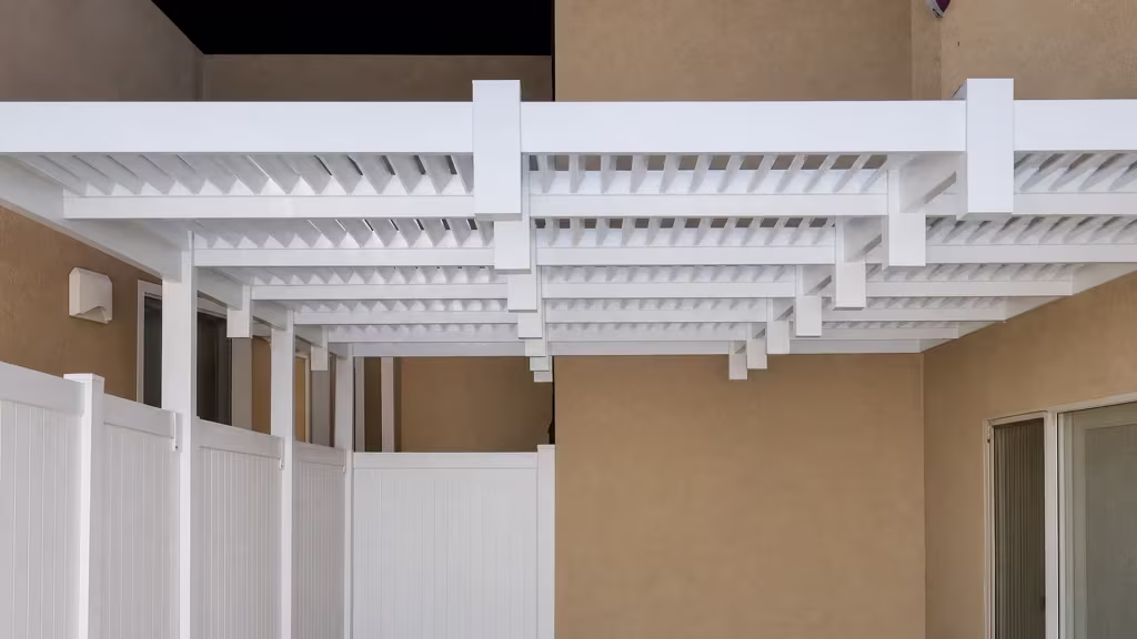 Two square posts and a fascia beam frame this louvered patio cover, custom fitted in White vinyl, above a railing partition