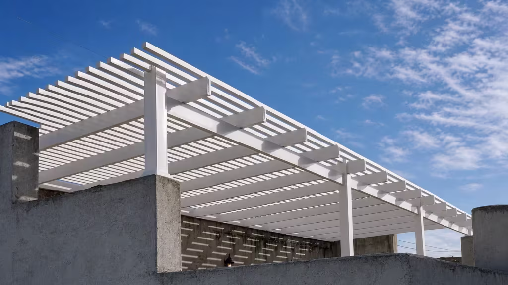Squared cross-member ends and dense pickets fill this picket patio cover, custom built in White vinyl, above a masonry wall