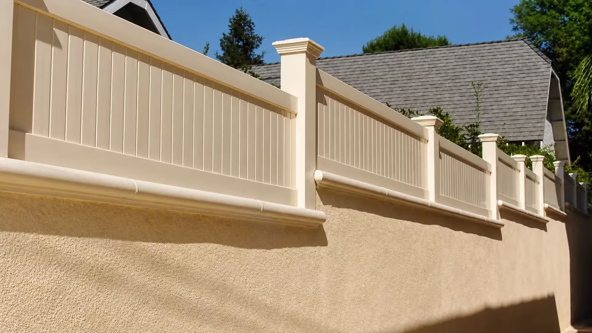 Tan custom vinyl wall topper spanning five panels along a stucco wall beneath palm foliage and rooflines