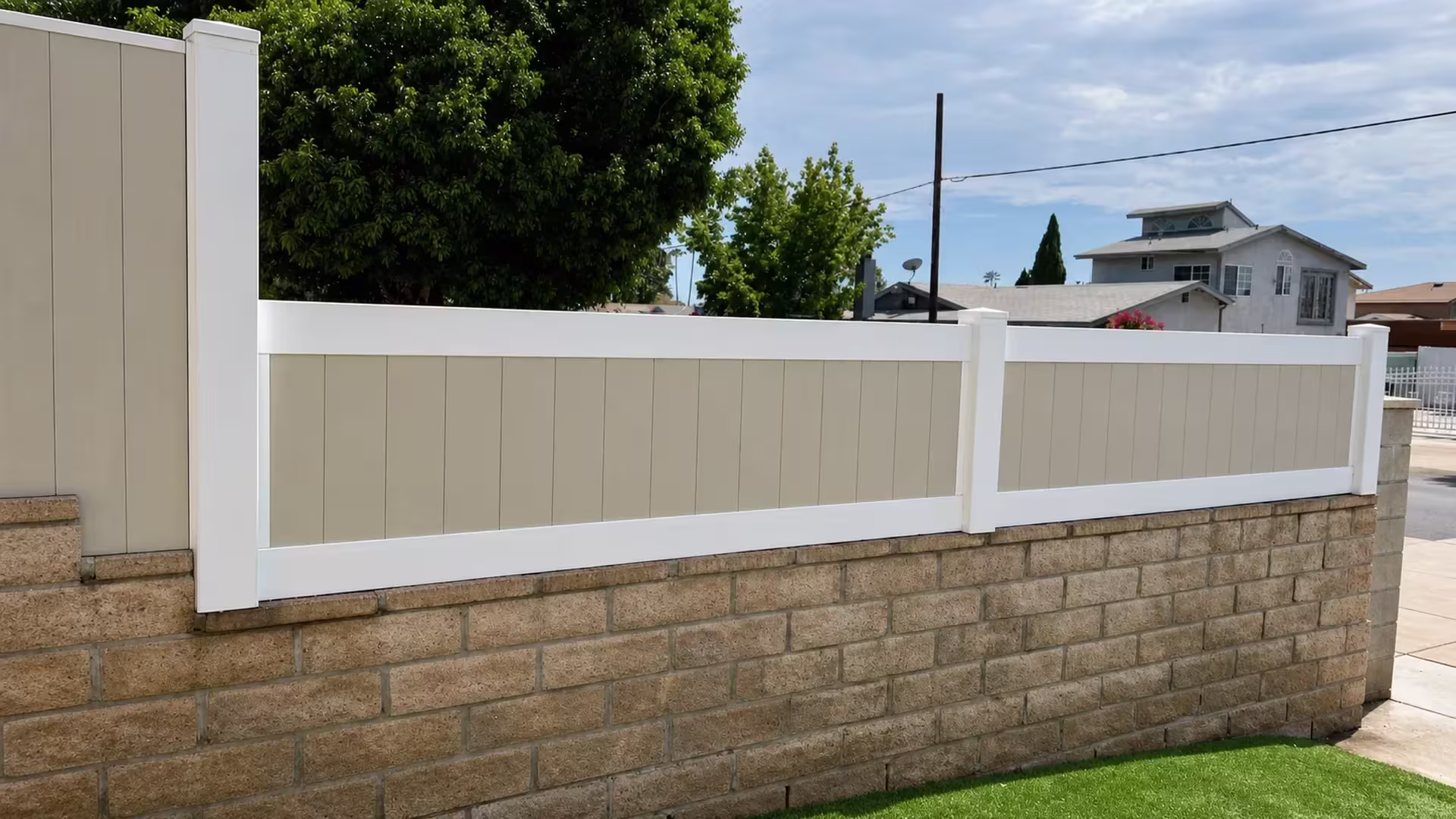 Two side panels of a Tan custom vinyl wall topper share a center post above an artificial turf yard