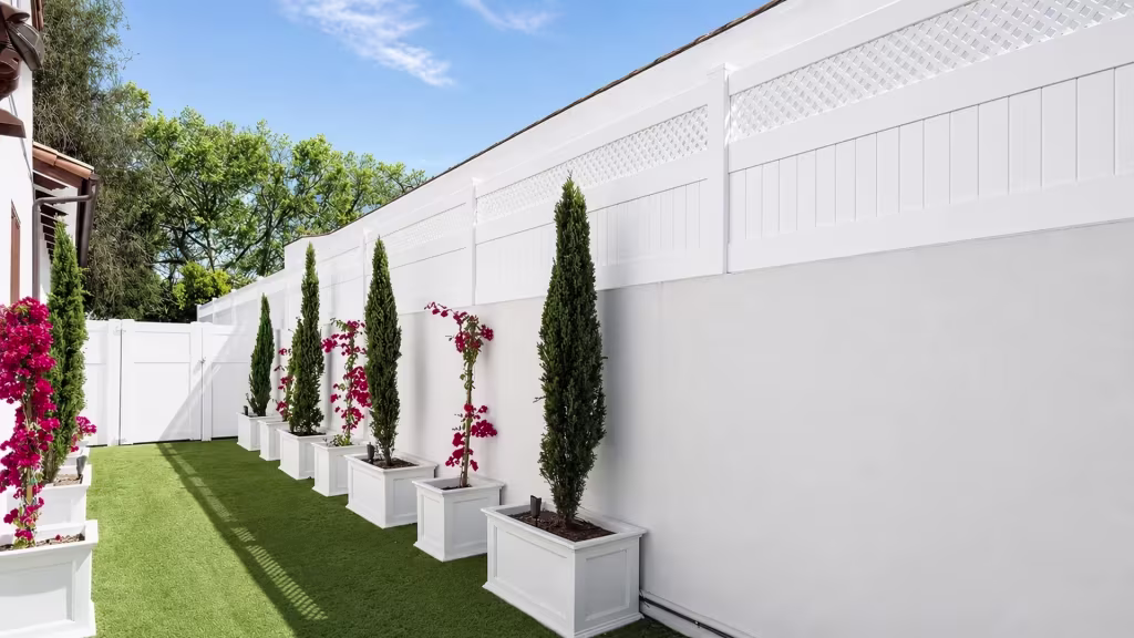 White custom vinyl wall topper with a diagonal lattice band above solid boards beside a turf path and planter boxes