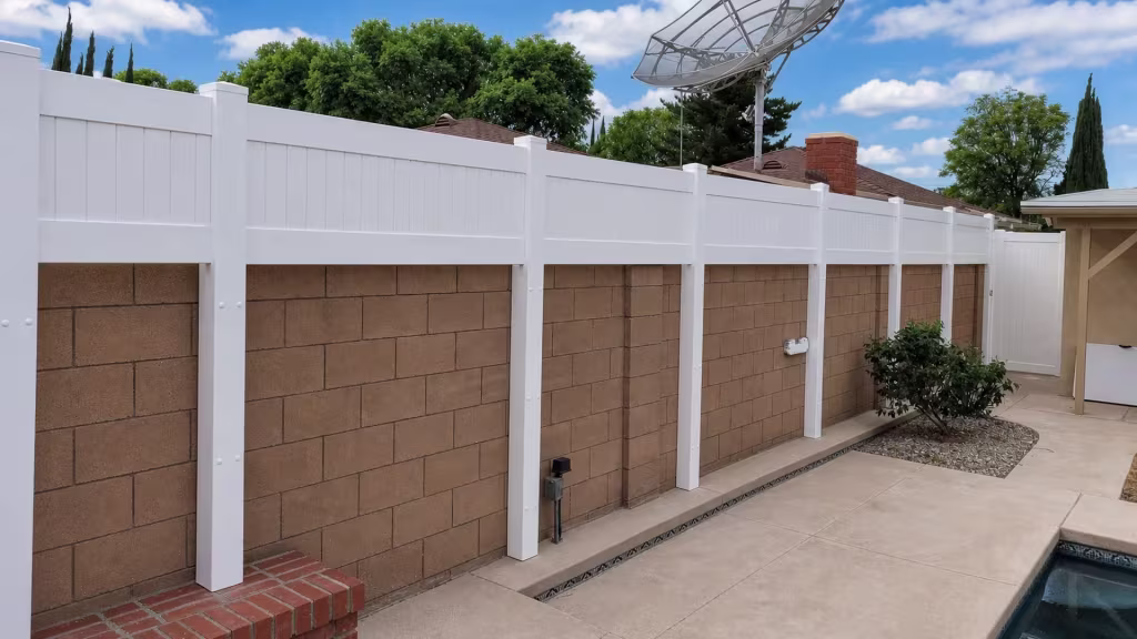 Near the pool edge, a brown block wall supports a White custom vinyl wall topper beside a chimney