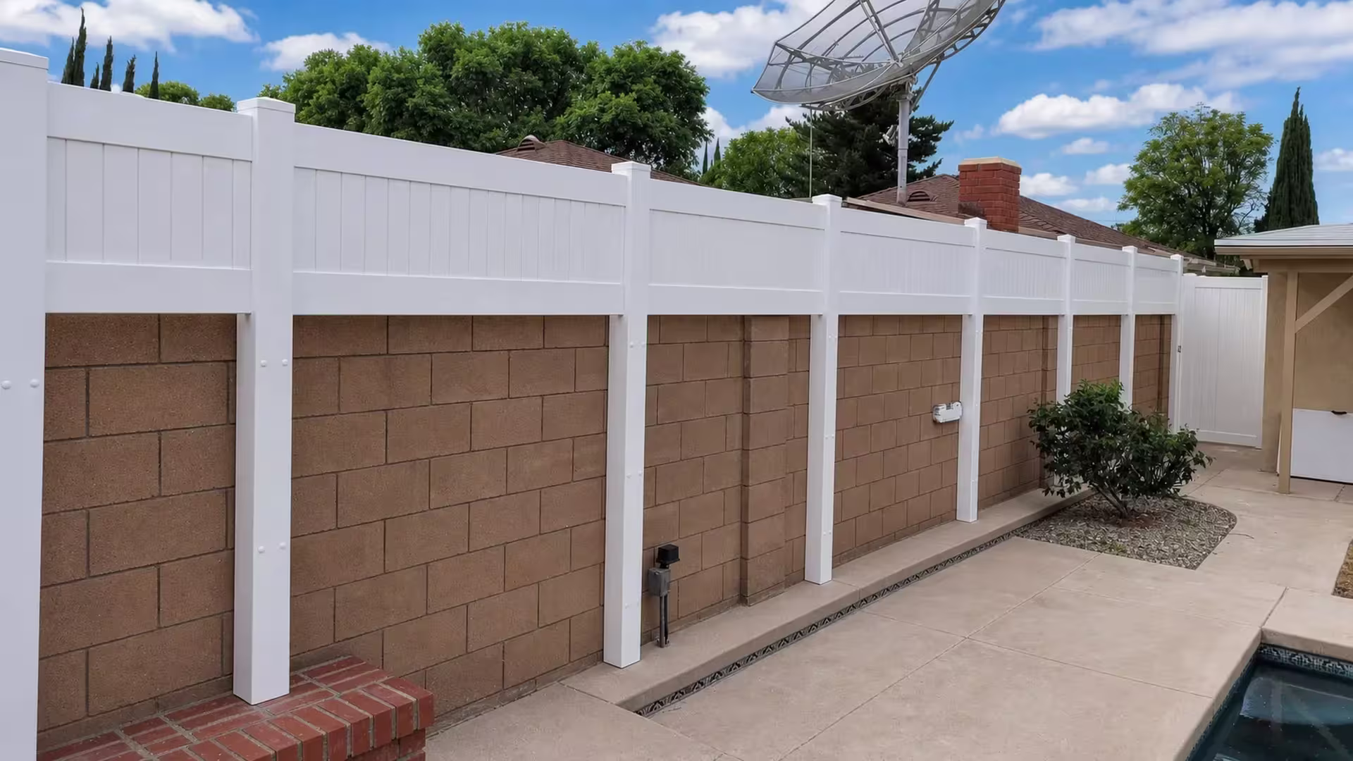 Near the pool edge, a brown block wall supports a White custom vinyl wall topper beside a chimney