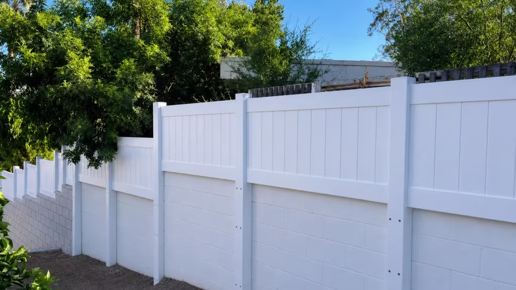 A block wall, stepped with piers and height changes, holds a White custom vinyl wall topper along its run