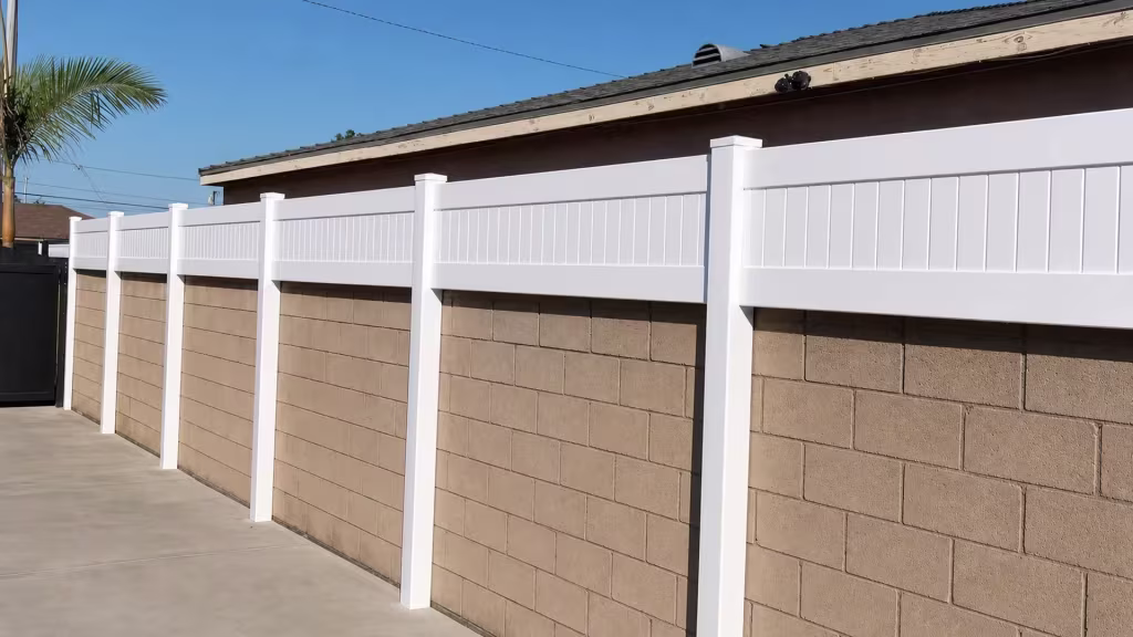 White custom vinyl wall topper fastened along a tan concrete block wall with six tall posts and stepped caps