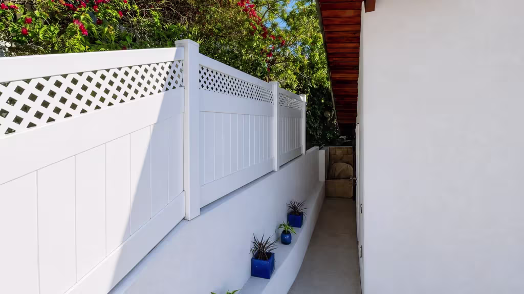 A walkway wall carries a White custom vinyl wall topper beneath dark timber eaves and blue plant pots